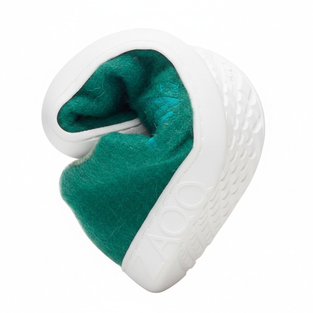 Der LIQE Green von ZAQQ zeichnet sich durch ein einzigartiges, gedrehtes Design aus, das an eine Sneakersohle mit einem strukturierten schwarz-weißen Muster erinnert und mit einem grünen, filzartigen Material gefüttert ist. Er ist so gefertigt, dass er einem Barfußschuh ähnelt, wobei der Markenname ZAQQ auf der Seite sichtbar ist.