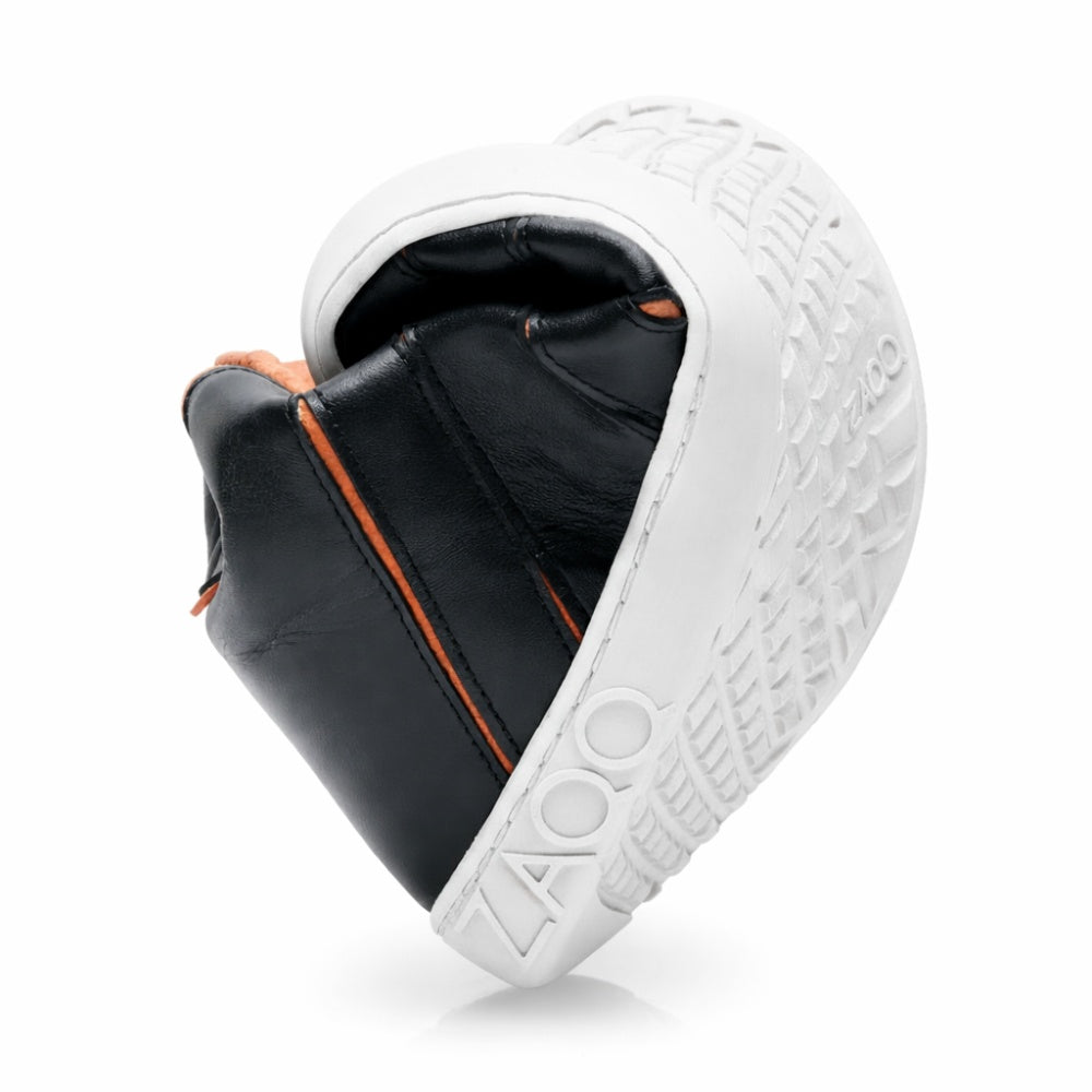 Der QQQ Mid Black Orange von ZAQQ zeigt seine Flexibilität, indem er sich in der Mitte biegt. Seine Kautschuksohle weist komplizierte Strukturmuster auf und „ZAQQ“ ist deutlich an der Seite zu sehen. Das elegante Design des Schuhs wird durch auffällige orangefarbene Nähte aufgewertet.