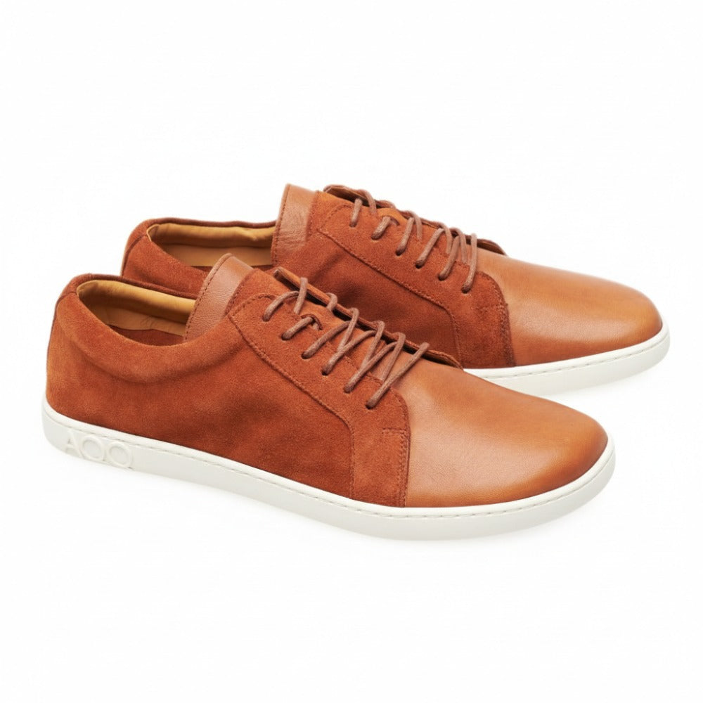 Die QORE Low Sierra Sneaker von ZAQQ sind ein stylisches Paar aus glattem braunem Leder mit Wildledereinsätzen und weißen Sohlen mit geprägten Details. Diese Schuhe haben braune Schnürsenkel und zeigen ein lässiges und modernes Design.